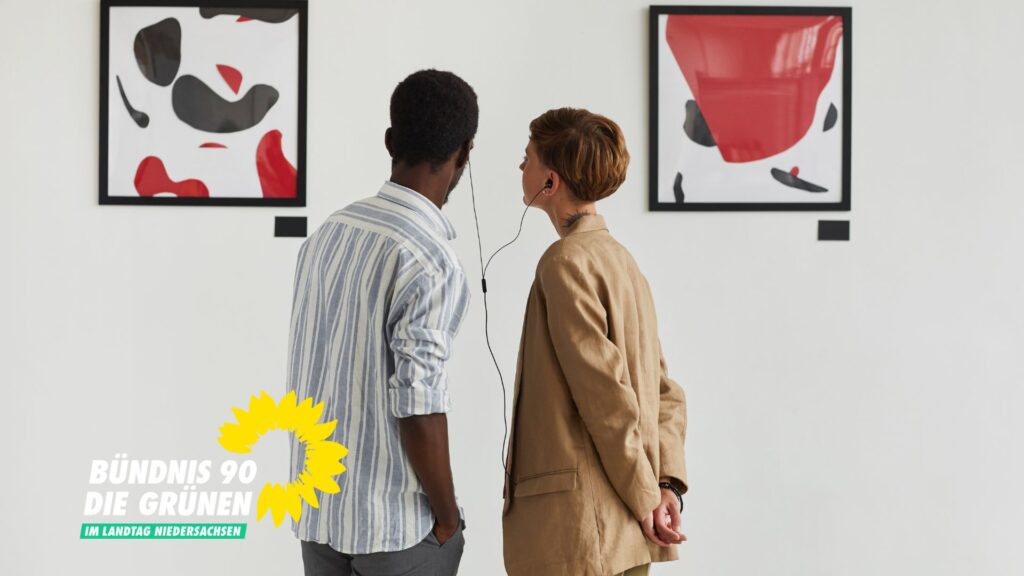 Zwei Personen lauschen ihrem Audioguide, während sie zwei Bilder an der Wand betrachten.