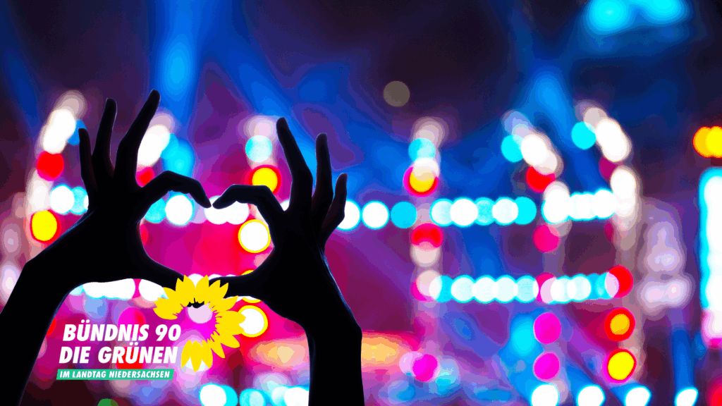 Zwei Händen formen ein Herz vor bunten Lichtern.