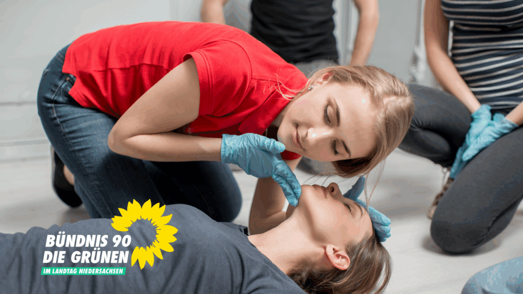 Eine Frau im roten T-Shirt beugt sich über eine am Boden liegende Frau und prüft deren Atmung.