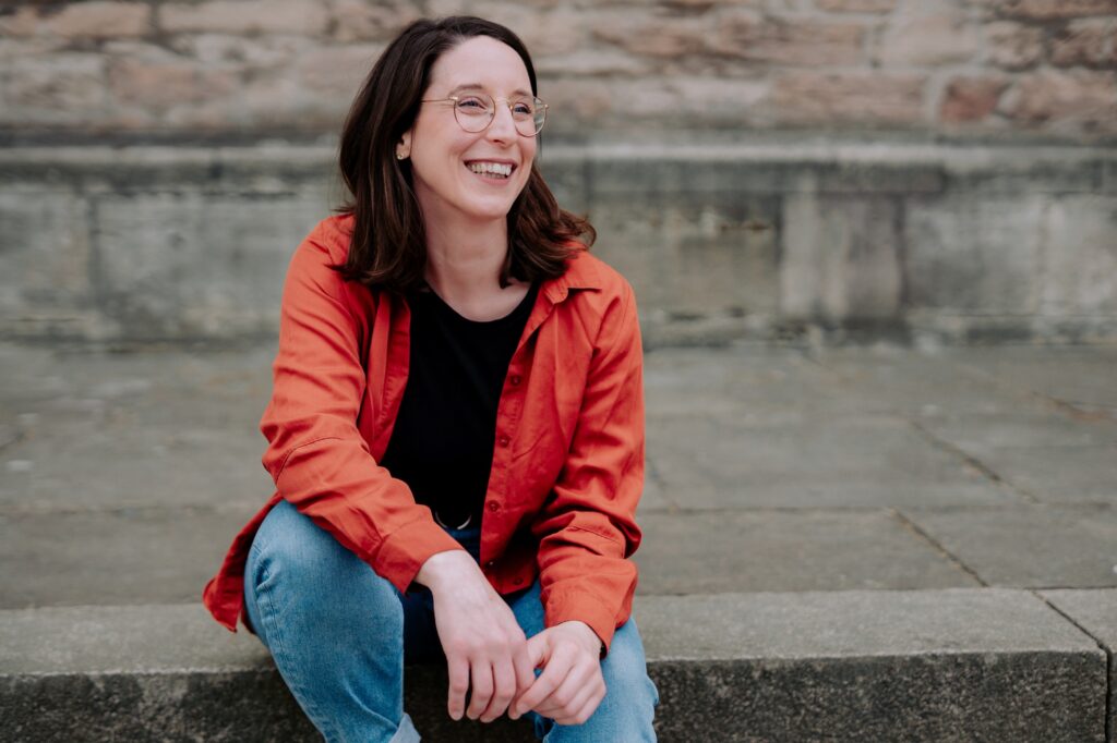 Swantje Schendel sitzt auf Treppenstufen und lacht fröhlich.