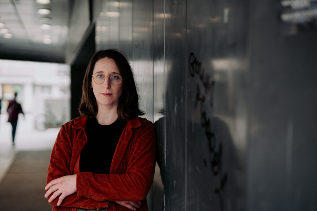 Swantje Schendel mit verschränkten Armen vor dunklem Hintergrund