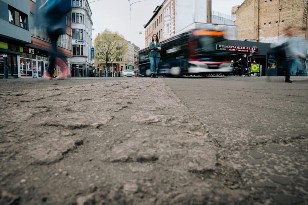 Swantje Schendel im Vordergrund, im Hintergrund fährt ein Bus vorbei.