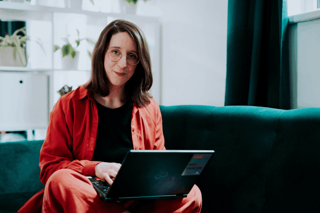 Swantje Schendel im Schneidersitz auf einem grünen Sofa mit einem Laptop auf dem Schoß.